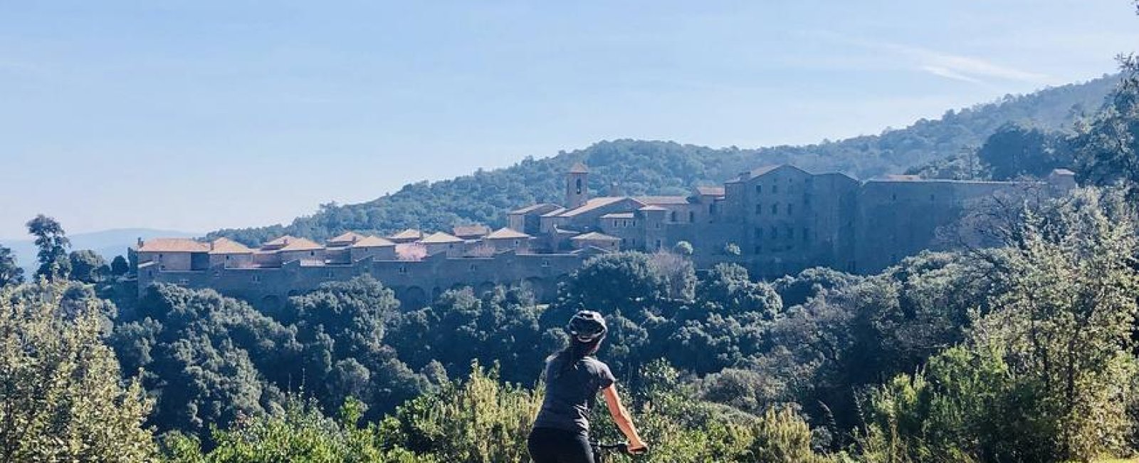Vttiste sur un sentier en terre avec la vue au loin de la Chartreuse de la Verne posée au milieu de la forêt des Maures