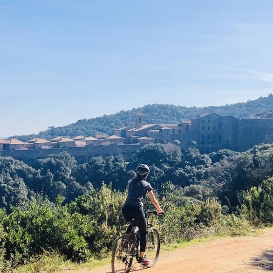 Vttiste sur un sentier en terre avec la vue au loin de la Chartreuse de la Verne posée au milieu de la forêt des Maures
